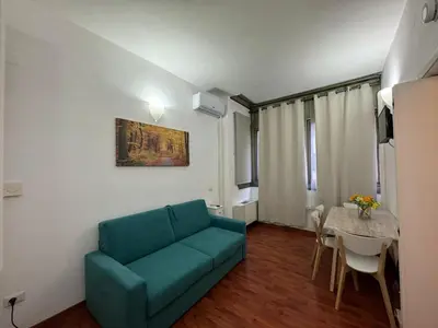 a living room with a blue couch and a table at San Giovanni's Cozy Apartment in Rome