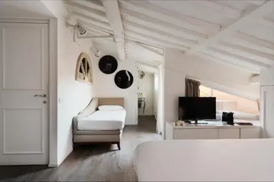 a white bedroom with a bed and a tv at BDB Rooms Trastevere in Rome