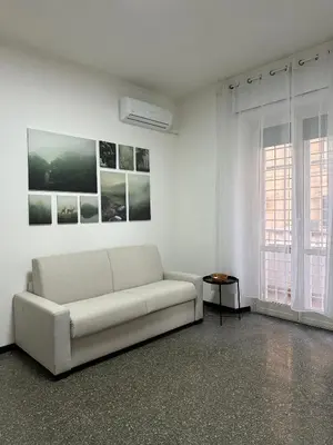 a white living room with a couch and two windows at Cozy House Roma - San Giovanni in Rome
