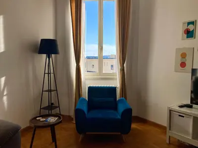 a living room with a blue chair and a window at Spazioso Appartamento Vicino al Vaticano in Rome