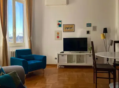 a living room with a tv and a blue chair at Spazioso Appartamento Vicino al Vaticano in Rome