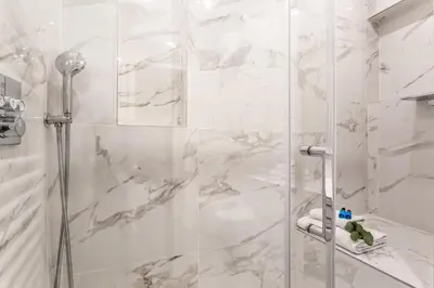 a bathroom with a shower with white marble walls at iFlat Augustus Suite near Pantheon in Rome