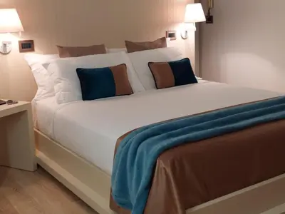 a large white bed with blue and brown pillows at La Dimora di Roma in Rome