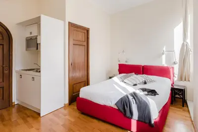 a red bed in a white room with a kitchen at Residenza del Cedro in Rome