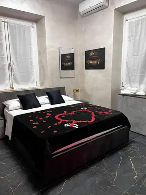 a bedroom with a large bed with red flowers on it at Gold House Roma in Rome