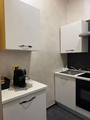 a kitchen with white cabinets and a black appliance on a counter at Gold House Roma in Rome