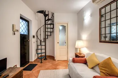 a living room with a couch and a spiral staircase at Charlotte Luxury Home Coronari in Rome