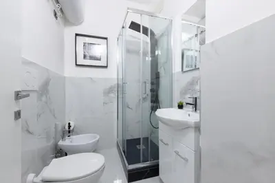a white bathroom with a shower and a toilet and sink at San Paolo Suites Metro Station in Rome