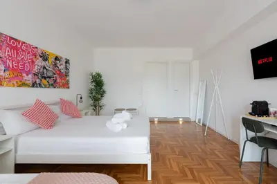 a white bedroom with a white bed and a wooden floor at San Paolo Suites Metro Station in Rome
