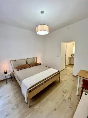a white bedroom with a large bed and a table at Pamphili Home - Un angolo di pace vicino Trastevere in Rome
