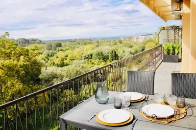 a table with plates and wine glasses on a balcony at Conca d'oro house in Rome