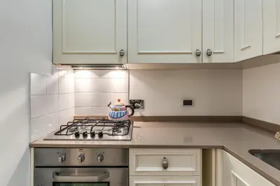 a kitchen with white cabinets and a stove top oven at Ciancaleoni Gruppo M&L Apartments in Rome