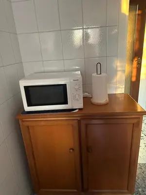 a microwave sitting on top of a wooden cabinet at Silvia's Home in Rome