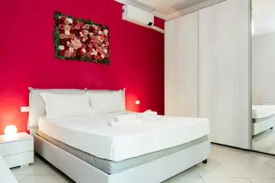a bedroom with a white bed with a red wall at Romantic Malatesta in Rome