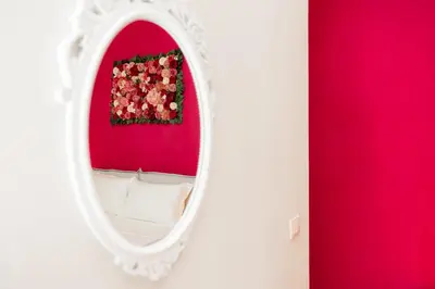 a white mirror in a room with a red wall at Romantic Malatesta in Rome