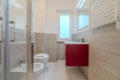 a bathroom with a white toilet and a red cabinet at Journalist Apartment Sistine Chapel in Rome