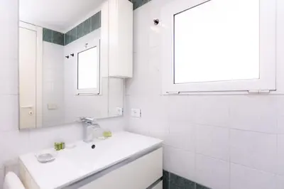 a white bathroom with a sink and a window at Centro Piccolo attico da sogno in Rome