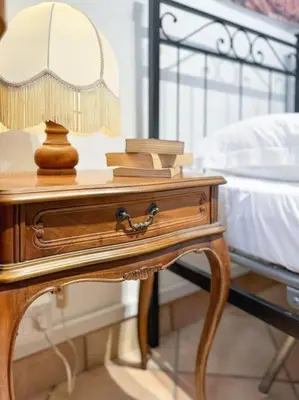 a wooden table with a lamp on it next to a bed at Vatican Art Apartment in Rome