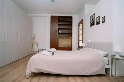 a bedroom with a white bed and a wooden floor at La Dolce Vita rooms in Rome