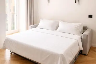 a bed with white sheets and pillows in a room at Vatican Boutique - 1 bedroom Apartment - Bilocale in Rome