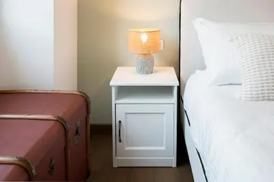 a white nightstand with a lamp on it next to a bed at AndreaSuite Gianicolo in Rome
