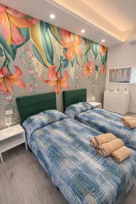 two beds in a room with flowers on the wall at Suite Maison San Pietro , Vaticano, AC & Wi-Fi in Rome