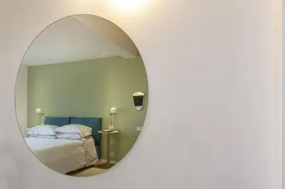 a mirror reflecting a bedroom with a bed in it at Luxe Vatican Penthouse in Rome