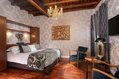 a bedroom with a bed and a chair and a chandelier at The Inn at the Spanish Steps Luxury Collection - Bocca di Leone 63 Luxury Suites in Rome