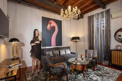 a woman standing in a living room with a painting of a flamingo at The Inn at the Spanish Steps Luxury Collection - Bocca di Leone 63 Luxury Suites in Rome