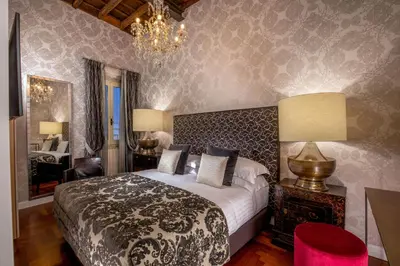 a bedroom with a large bed and a chandelier at The Inn at the Spanish Steps Luxury Collection - Bocca di Leone 63 Luxury Suites in Rome