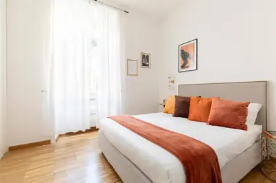 a white bedroom with a large bed with orange pillows at YCH-Charming home near San Giovanni in Rome