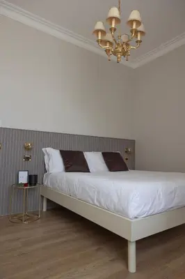 a bedroom with a large white bed with a chandelier at Tiburtina 86 Luxury Suites in Rome