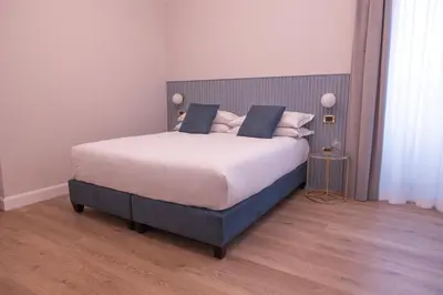 a bedroom with a large bed with white sheets and blue pillows at Tiburtina 86 Luxury Suites in Rome