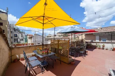 a patio with a table and a yellow umbrella at Monti 3 bedroom apartment Colisseum in Rome
