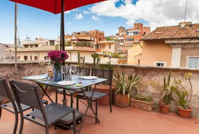 a table with chairs and an umbrella on a balcony at Monti 3 bedroom apartment Colisseum in Rome