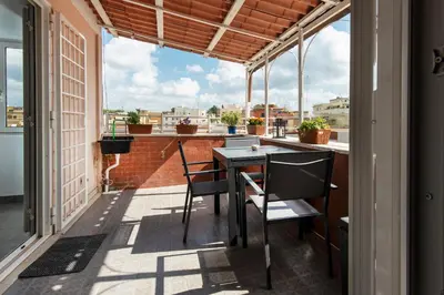 a balcony with a table and chairs and windows at Attichetto Monteverde in Rome