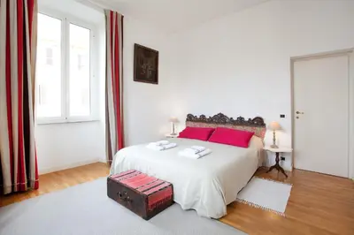 a white bedroom with a large bed with red pillows at B&B Ondina in Rome