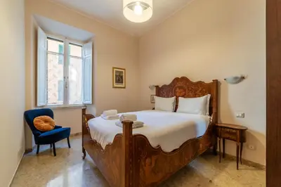 a bedroom with a large bed and a blue chair at GuestHost - Sapienza University Elegant Apartment! in Rome