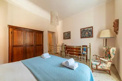 a bedroom with a bed with a blue blanket and a chair at GuestHost - Sapienza University Elegant Apartment! in Rome