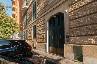 a car parked next to a building with a green door at GuestHost - Sapienza University Elegant Apartment! in Rome