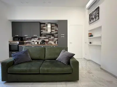 a green couch in a living room with a kitchen at Green apartment a Porta Pia in Rome