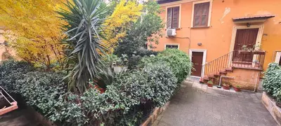 a house with a palm tree in front of a building at Trastevere incantevole con patio esterno privato in Rome