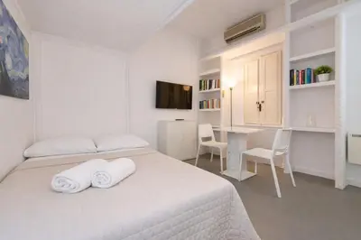 a white bedroom with a bed and a window at Condotti Loft - city center in Rome