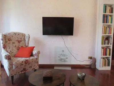 a living room with a chair and a television on a wall at Maddy House Roma in Rome