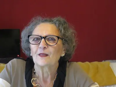 an older woman wearing glasses sitting on a couch at Maddy House Roma in Rome
