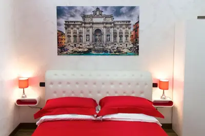 a bedroom with a red bed with a painting on the wall at Luxury Rome Savini Guest House in Rome