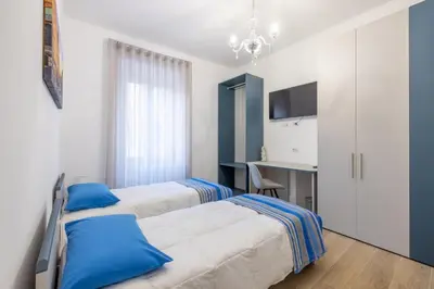 a bedroom with two beds with blue pillows and a desk at Blessed House in Rome