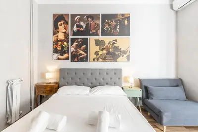 a bedroom with a white bed and a blue couch at Vatican 2bedr apt in Rome