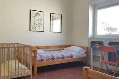 a bedroom with a crib and a bed and a chair at Casa Marconi apt in Rome