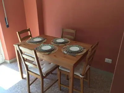 a wooden table with four chairs and plates on it at Casa Marconi apt in Rome
